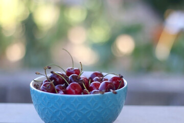 Bowl of fresh cherries, served in a garden. Selective focus.