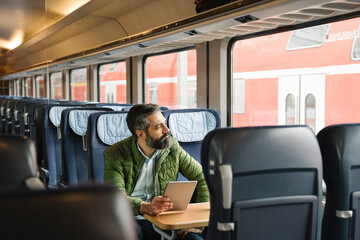 Man sitting in train holding tablet