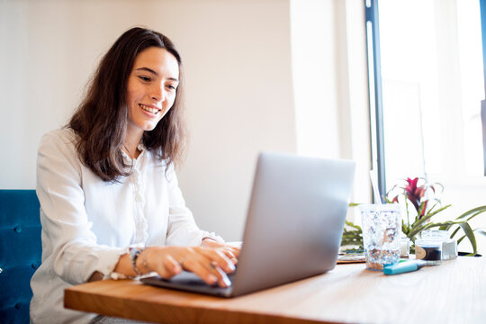 Portrait of smiling young woman working on laptop at home office