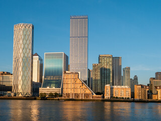 Financial district buildings in Canary Wharf area of London illuminated at sunset against the blue...