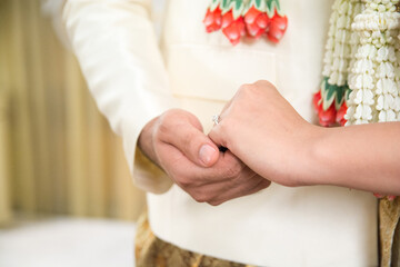 close up groom and bride hand in wedding ceremony Thai suite