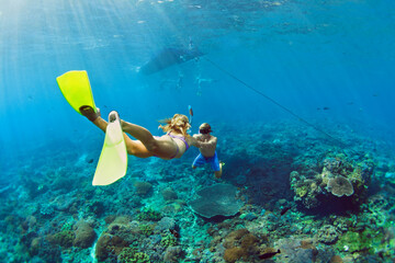 Happy family vacation. Young couple in snorkeling mask hold hand, free dive underwater with fishes...