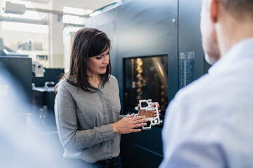 Businesswoman showing product to businessman in a factory