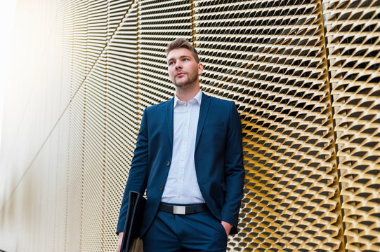 Portrait of a young businessman leaning against a facade