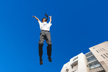Fototapeta na wymiar 青空を背景にジャンプをする男子高校生