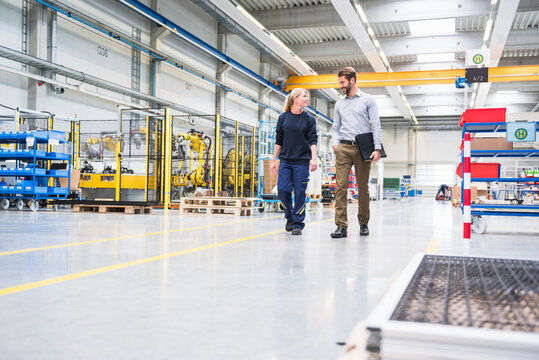 Man and a woman walking and talking in a factory