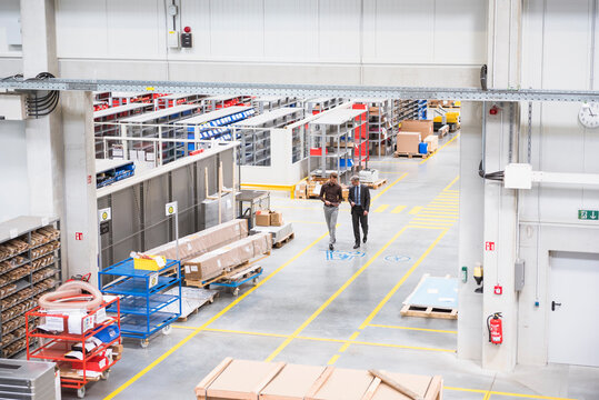 Two businessmen walking on factory shop floor