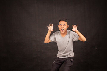 Angry and hate face of Young Asian man in gray shirt with angry hand gesture.