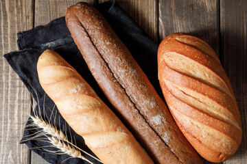 Variety of loaves of bread and baguette on wooden table background