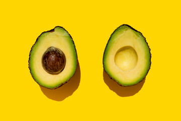 Studio shot of halved avocado on yellow background