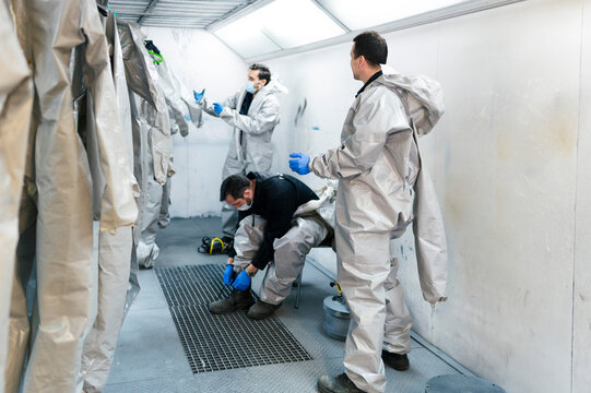 Sanitation Workers Getting Dressed In Protective Coveralls Inside Locker Room