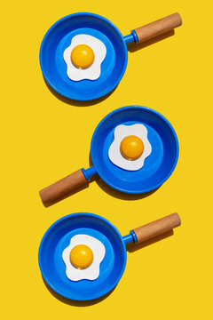 Illustration of fried eggs on blue pans against yellow background