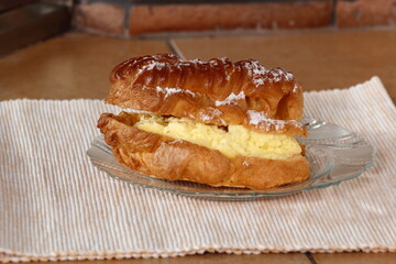 Eclair filled with pastry cream (custard) and topped with icing sugar