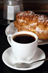 Coffee cup with espresso and eclair