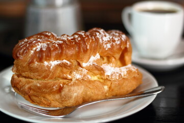 Eclair and coffee cup with espresso