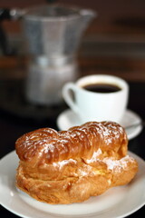 Eclair and coffee cup with espresso