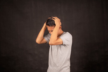 Young Asian man in gray t-shirt Feeling sick and tired. Frustrated and stressed young man touch his face.