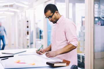 Concentrated on work skilled male engineer thinking over solution of technical problem in outlay...
