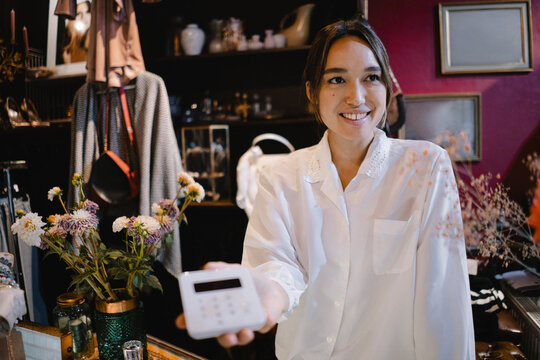 Confident owner holding credit card reader at thrift store