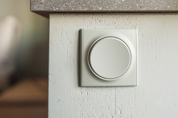 Gray round switch on the wall under the windowsill, close-up