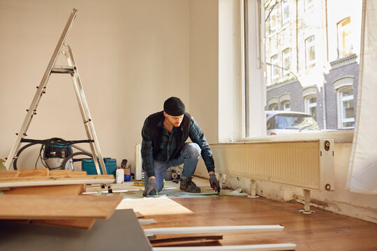 Man refurbishing shop location, laying flooring