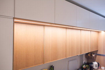 Kitchen cabinets, shelves with lighting, doors oak veneer and white. Close-up.