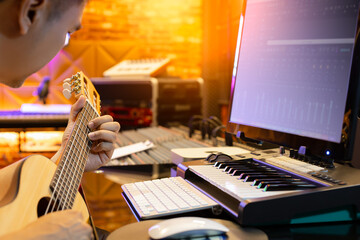 asian man learning acoustic guitar lesson from internet in sound studio
