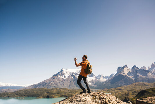 Hiker cheering in mountainscape at Lago Pehoe in Torres del Paine National Park, Patagonia, Chile