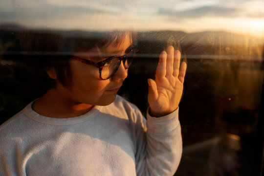 Portrait of little boy behind windowpane watching sunset