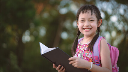 Happy school girl reading book with backpack.Back to school concept , 16:9 Style