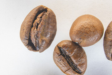 Brown coffee grains on a white paper background. Fragrant coffee grains close-up.