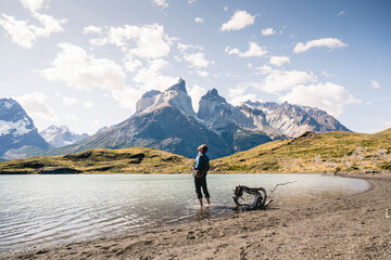 Hiker in mountainscape standing in a lake in Torres del Paine National Park, Patagonia, Chile
