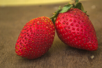 two red strawberries on a wooden surface