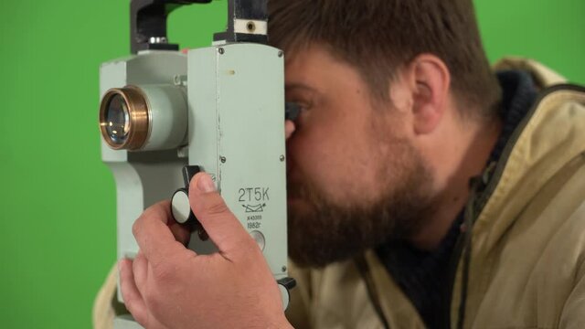 This close-up clip features a surveyor looking into a theodolite against a green screen.