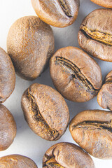 Brown coffee grains on a white paper background. Fragrant coffee grains close-up.