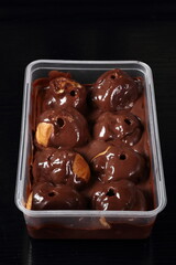 Box with profiterole with chocolate ganache frosting.