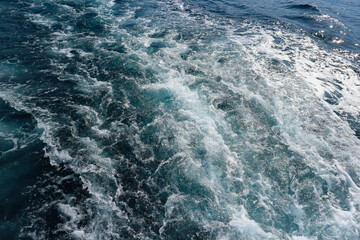 Speedboat leaving white foam and trail of wakes behind