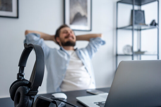 Man leaning back at desk, focus on headphone