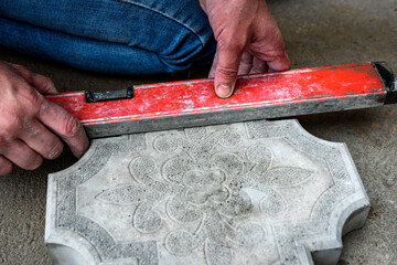Worker hands marking concrete tile to be cut.