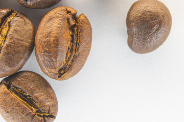 Brown coffee grains on a white paper background. Fragrant coffee grains close-up.