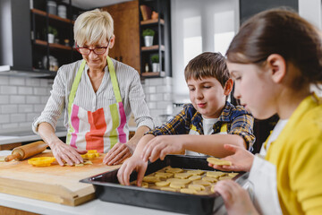 Grandmother baking cookies with her grandchildren at home. Baking cookies. Happy grandmother with her grandchildren having fun