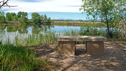 Rock bench with a view of the Rocky Mountains from Arapaho Bend Natural Area in fort Collins, Colorado.