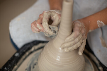 Making ceramic utensils.The master handles jug, giving it the correct shape. Ceramist working on the wheel of a potter making an ewer.
