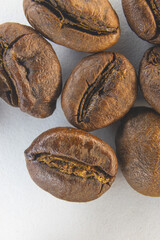 Brown coffee grains on a white paper background. Fragrant coffee grains close-up.