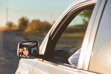 Fototapeta na wymiar gorgeous woman in sunglasses reflection in car mirror on sunset