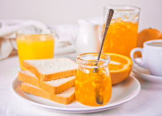 Bread toast with orange jam, glasses of orange juice on the white background. Breakfast concept.