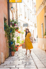 Fototapeta na wymiar tourist woman in yellow sundress walking by small croatian city street