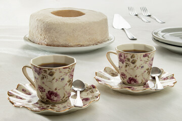 white cake cut on the table whith coffee cups