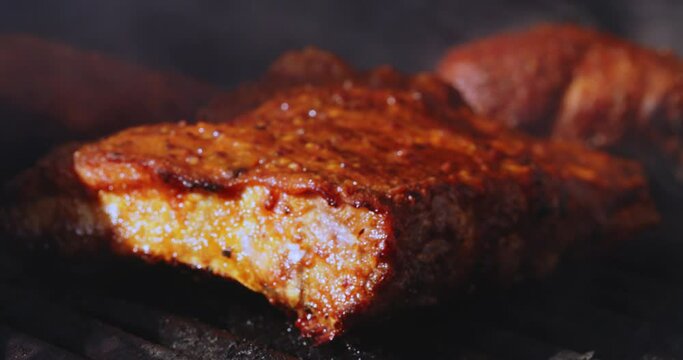 Close up of juicy rack of ribs cooking on a bbq grill on a summer afternoon