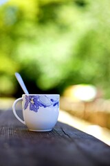 Tasse à Café sur une table en bois de campagne avec nature verte derrière.